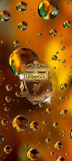 the liverpool football club logo is surrounded by water droplets on a yellow and orange background