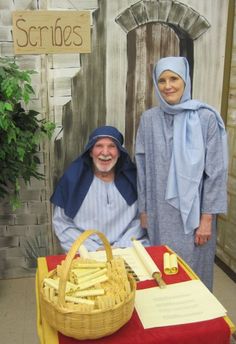 two people in costumes standing next to a table with bread and cheeses on it