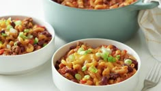 two bowls filled with macaroni and cheese on top of a white tablecloth