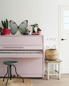 a pink piano sitting in the corner of a room with potted plants on it