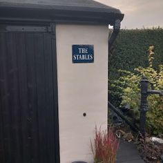 there is a small building with a sign on the door and some plants around it