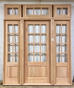 two wooden doors sitting next to each other in front of a white brick wall with windows