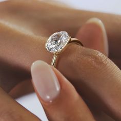 a woman's hand holding an engagement ring with a diamond on it and the other hand