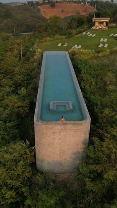 an aerial view of a swimming pool in the middle of some trees and bushes,