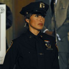 a woman police officer standing in front of other people and looking off to the side