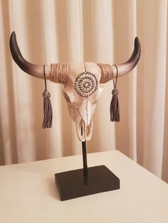 a cow skull with long horns and tassels on it's head sitting on a table