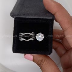 a person holding a ring in a black box with a white diamond on the inside