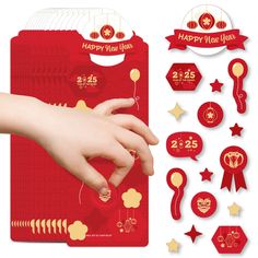 a hand is touching the back of a red envelope with gold decorations and stars around it