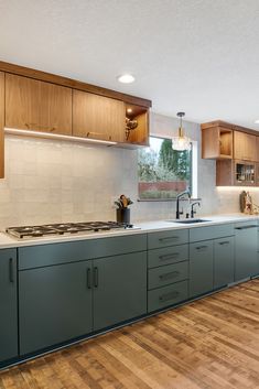 a kitchen with wooden floors and cabinets in the middle, along with a stove top oven