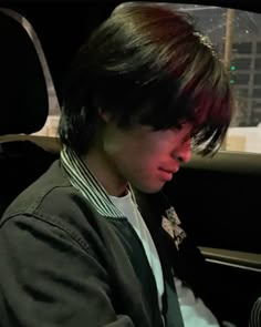 a young man sitting in the back seat of a car