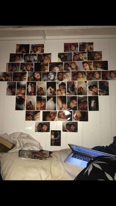 a wall with many pictures on it and a laptop in the foreground, next to a bed