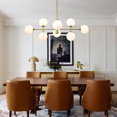 a dining room table with brown chairs and an art work on the wall behind it