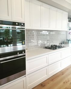 a kitchen with white cabinets and black stove top ovens in front of a window