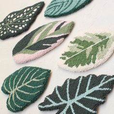 four different leaf shaped rugs on a white surface with green and pink leaves in the middle