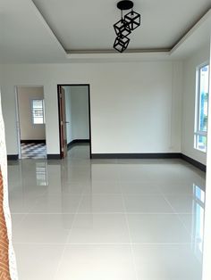 an empty room with white tile floors and black trim on the ceiling is seen in this image