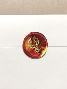 a close up of a button on a piece of white paper with a gold dragon