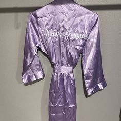 a purple robe hanging on a wall with the word maid of honor written on it