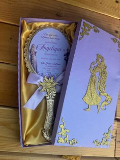 a purple and gold wedding card in a box with a princess silhouette on the front