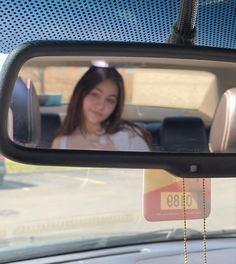 a woman is seen in the rear view mirror of a car as she sits inside