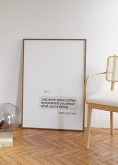 a white framed poster sitting on top of a hard wood floor next to a chair