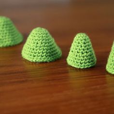 small crocheted green cones sitting on top of a wooden table next to each other