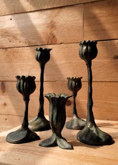 four metal candlesticks sitting on top of a wooden table