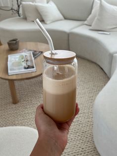 a person holding a glass with a straw in it on top of a coffee table