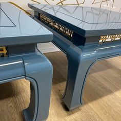 a blue table with two matching stools on the bottom, and a wall in the background