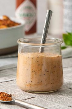 a glass jar filled with food sitting on top of a table next to a spoon