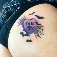 a pregnant woman with a tattoo on her stomach that says bite me and bats in the background