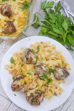 a plate of pasta with meatballs and parsley next to a casserole dish