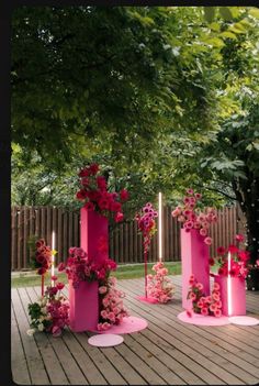 some pink candles and flowers on a wooden deck