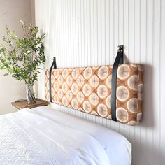 a bed with a white comforter and a wooden headboard hanging on the wall