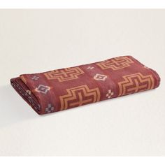 a red and brown blanket sitting on top of a white table