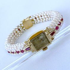 Beautiful One of A Kind stunning vintage working Winding Dial Watch is reworked into a timeless and elegant Pearl, Ruby and 14k Yellow Gold piece. Stamped and made in all solid 14k Yellow Gold, this timeless watch is revived by Tapered Baguette Rubies set on each side which perfectly contrasts the 14k Yellow Gold. A stunning band of round white Seed Pearls, Faceted Rubies and solid 14k Yellow Gold findings are all intricately woven together to frame this vintage piece. This top of the band is wo Vintage 14k Stamped Jewelry For Formal Occasions, Classic Yellow Gold Jewelry And Watches For Anniversary, Classic Watch With Box Clasp For Anniversary, Classic Yellow Gold Diamond Watch With Jubilee Bracelet, Anniversary Yellow Gold Bracelet With Diamond Hour Markers, Yellow Gold Jewelry For Wedding, Yellow Gold Diamond Watch With 17 Jewels For Wedding, Timeless Yellow Gold Diamond Watch For Wedding, Heirloom Yellow Gold Jewelry