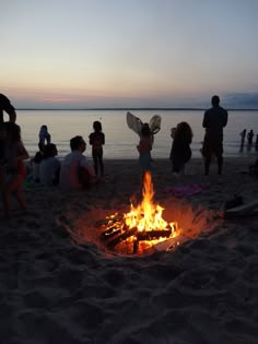 people standing around a fire pit on the beach