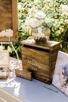 a wooden box sitting on top of a table next to pictures and flowers in vases