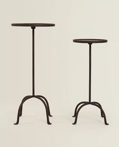 two black tables with metal legs and one has a round table top on each side