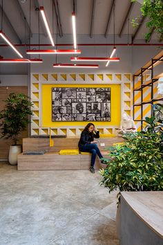 a woman sitting on the steps in front of a yellow and white wall with plants