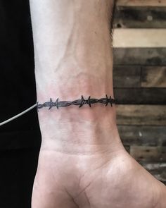 a man's wrist with a barbed wire tattoo on it