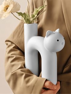 a person holding a vase with a flower in it and the letter h on it