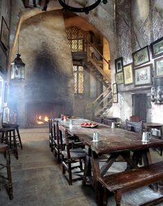 an old fashioned dining room with wooden tables and benches in front of a fire place