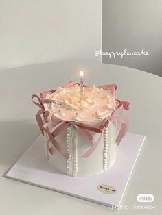 a birthday cake with a lit candle in the middle on top of a white table