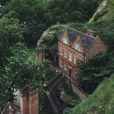 an aerial view of a brick building surrounded by trees and bushes with stairs leading up to it