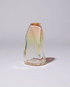 a small glass vase sitting on top of a table next to a white wall and floor