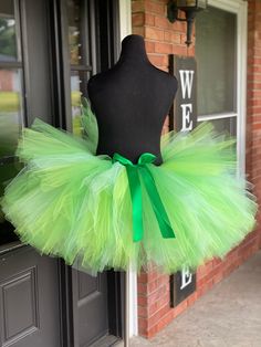 a mannequin wearing a green tutu in front of a door