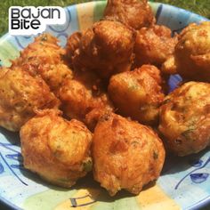 a blue and white plate topped with fried food on top of green grass covered ground