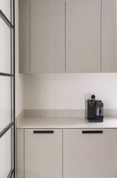 a kitchen counter with a coffee maker on it's top and cupboards in the background