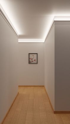 an empty room with wooden floors and white walls, framed artwork on the wall above