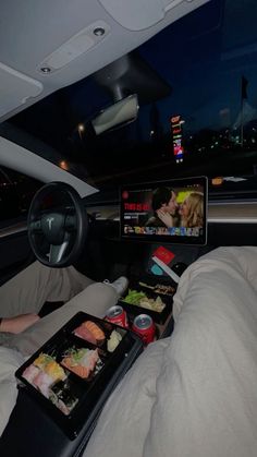 there is a tray of sushi in the back seat of a car with someone watching it